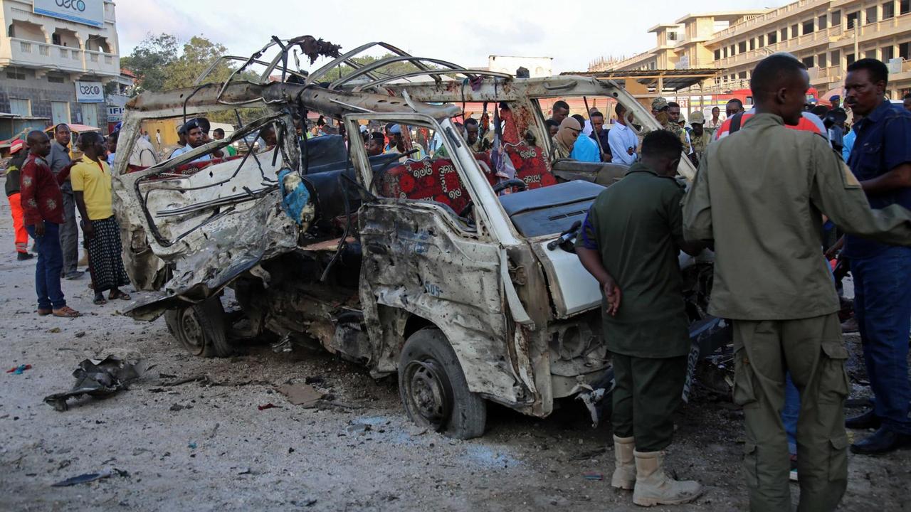 Sicherheitskräfte schauen in Mogadischu auf das Wrack eines explodierten Kleinbusses. Sicherheitskräfte schauen in Mogadischu auf das Wrack eines explodierten Kleinbusses.