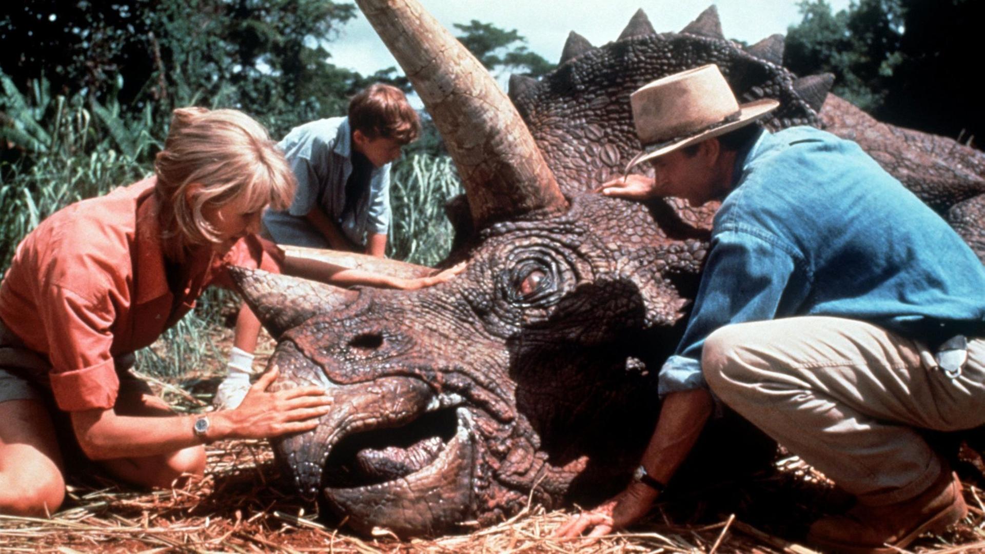 Die Schauspieler Laura Dern, Joseph Mazzelli und Sam Neil helfen einem kranken Dinosaurier. (Aufnahme von 1993). Im Film "Jurassic Park" experimentieren Wissenschaftler mit dem Erbgut von Dinosauriern, das sie in konservierten, blutsaugenden Insekten aus der Vorzeit entdecken. Es gelingt ihnen, selbst Dinosaurier heranzuzüchten, die später ihre Schöpfer terrorisieren. Die Schauspieler Laura Dern, Joseph Mazzelli und Sam Neil helfen einem kranken Dinosaurier. (Aufnahme von 1993). Im Film "Jurassic Park" experimentieren Wissenschaftler mit dem Erbgut von Dinosauriern, das sie in konservierten, blutsaugenden Insekten aus der Vorzeit entdecken. Es gelingt ihnen, selbst Dinosaurier heranzuzüchten, die später ihre Schöpfer terrorisieren.