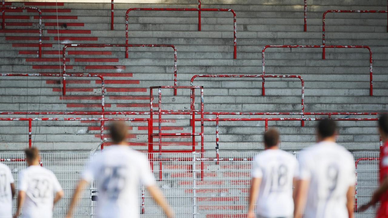 Leere Tribünen im Stadion an der Alten Försterei. Im Vordergrund, in der Unschärfe einige Spieler. Leere Tribünen im Stadion an der Alten Försterei. Im Vordergrund, in der Unschärfe einige Spieler.
