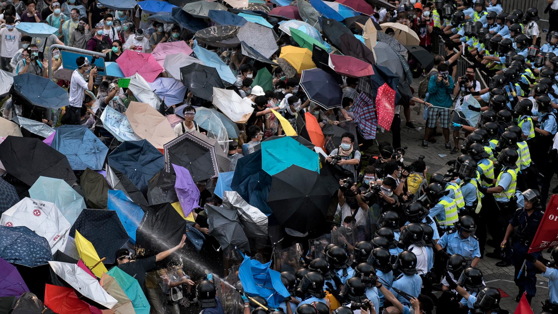 Demonstranten in Hongkong schützen sich mit Regenschirmen vor dem Pfefferspray der Polizei. Demonstranten in Hongkong schützen sich mit Regenschirmen vor dem Pfefferspray der Polizei.