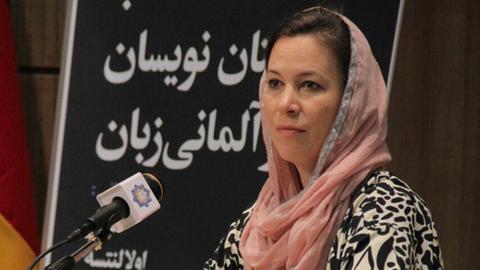 Die Schriftstellerin Ulla Lenze auf einem Podium in Teheran. Sie trägt ein Kopftuch so wie es im Iran für Frauen üblich ist.