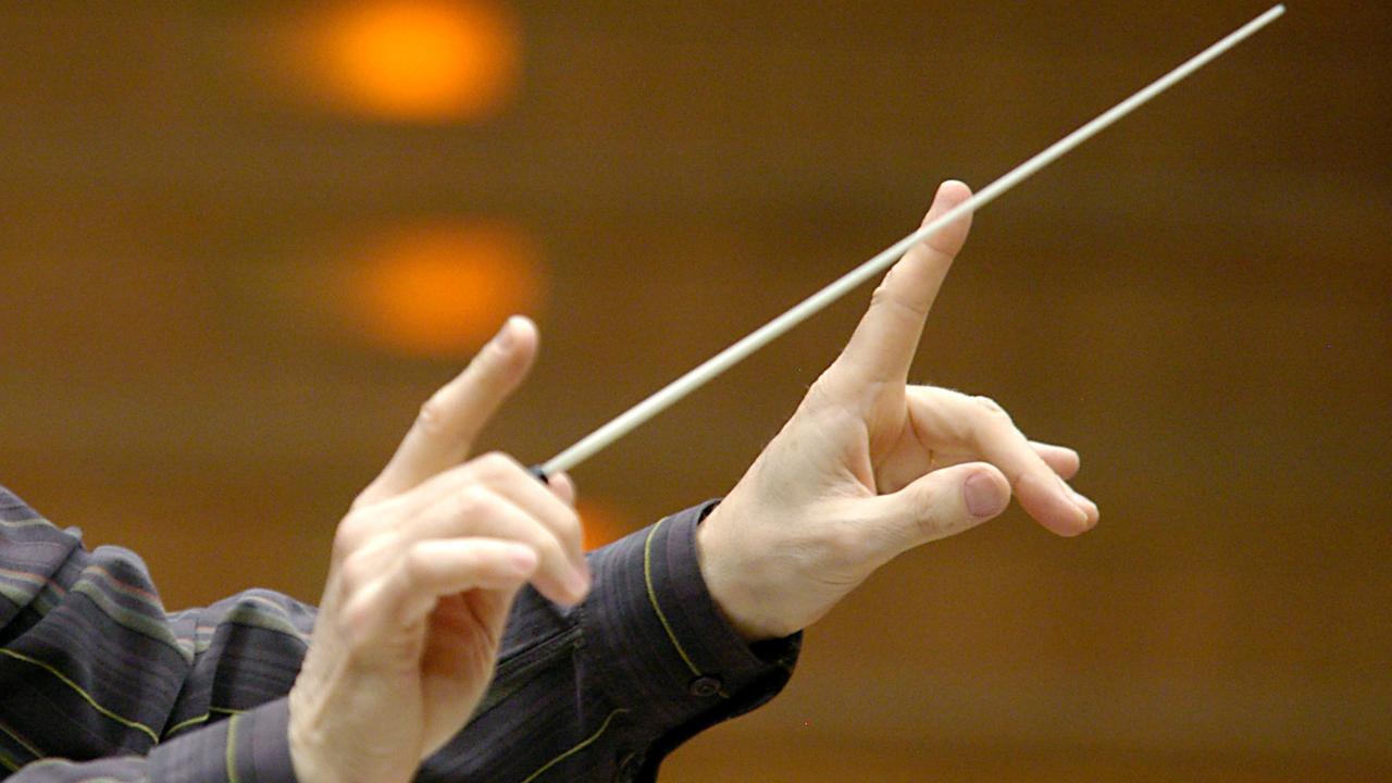 Zwei Hände dirigieren ein Orchester. Zwei Hände dirigieren ein Orchester.