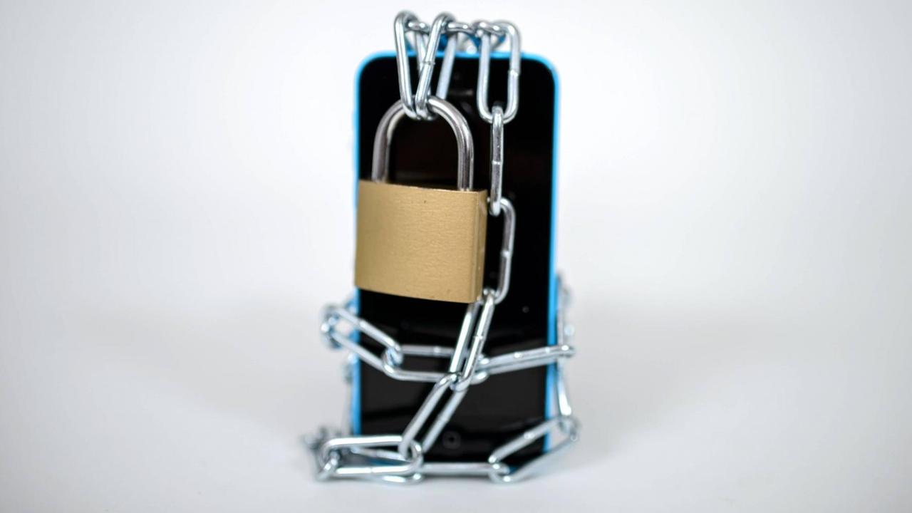Ein handy ist mit einem Schloss gesichert und kann nicht genutzt werden. Ein handy ist mit einem Schloss gesichert und kann nicht genutzt werden.