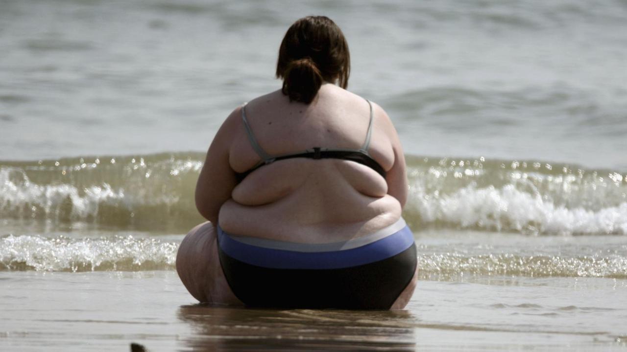 Eine dicke Frau sitzt am Strand. Eine dicke Frau sitzt am Strand.