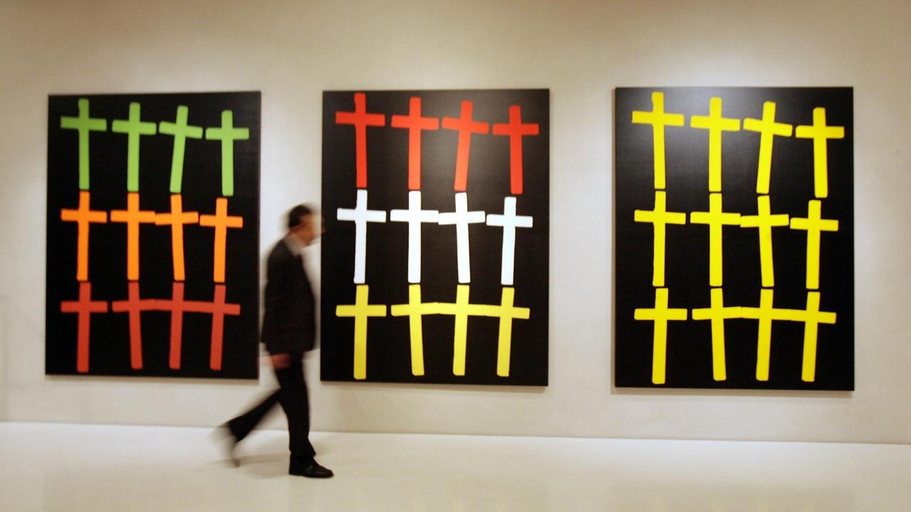 Ein Besucher des Kolumba, dem Kunstmuseum des Erzbistums Köln, betrachtet in einem Ausstellungsraum die Bilder "Crosses" von Andy Warhol.