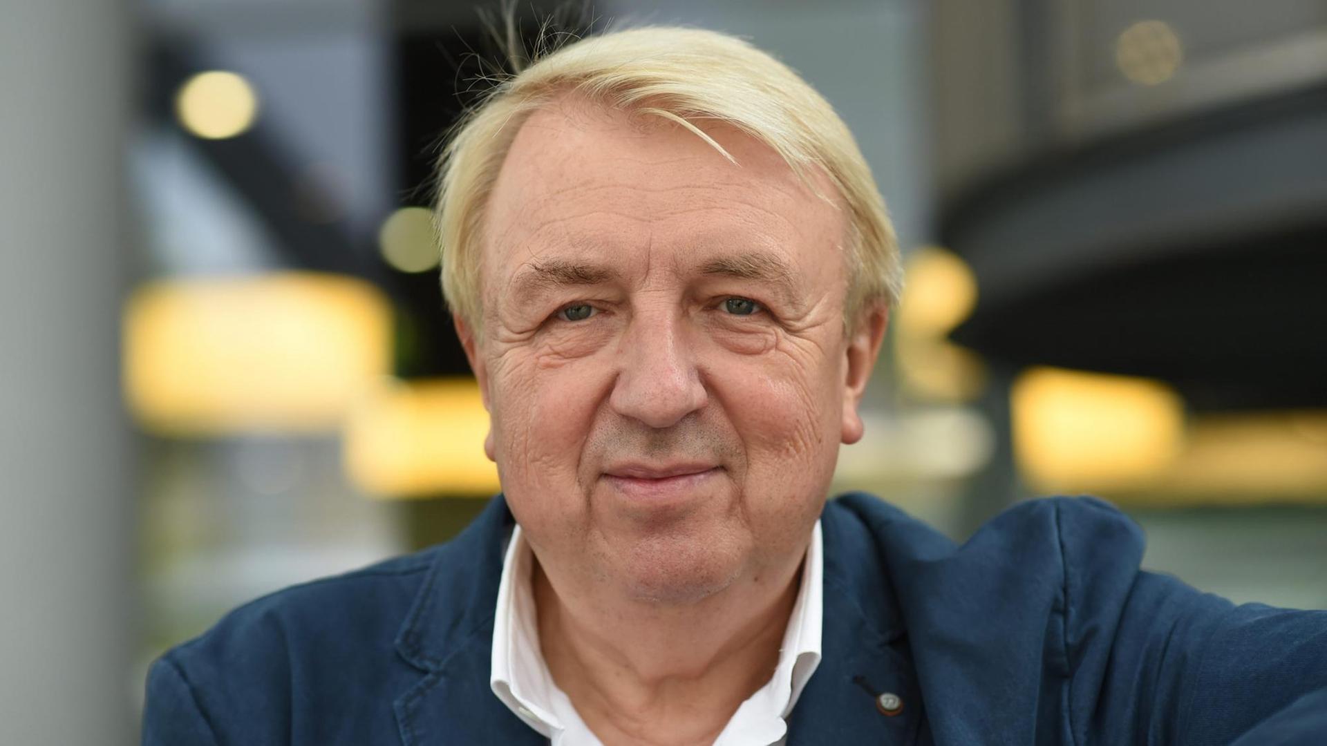 Hanns-Josef Ortheil hat blonde Haar und trägt ein weißes Hemd und dunkle Jacke. Er blickt in Richtung Kamera Hanns-Josef Ortheil hat blonde Haar und trägt ein weißes Hemd und dunkle Jacke. Er blickt in Richtung Kamera