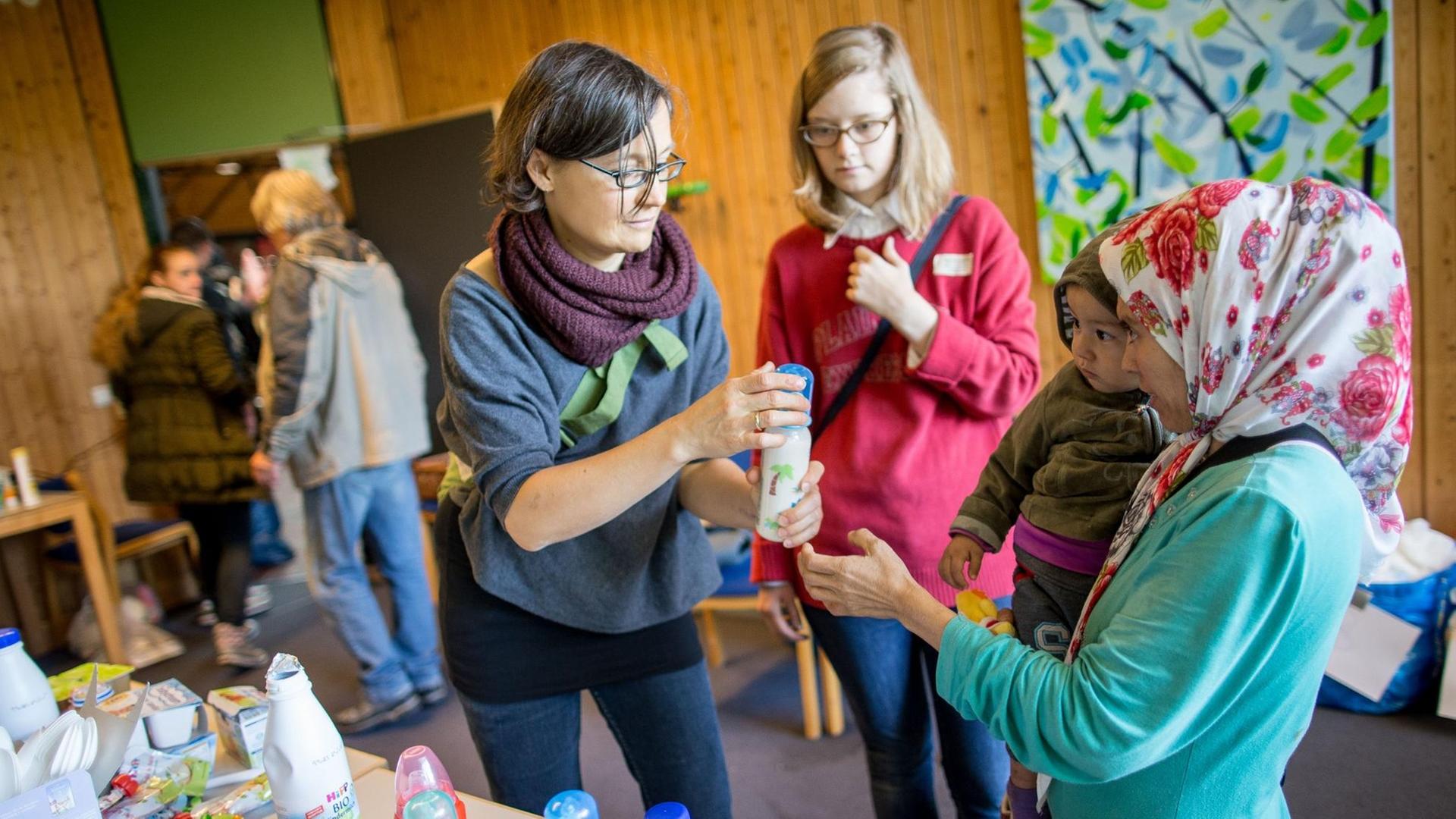 Eine Helferin gibt am 06.09.2015 in Dortmund (Nordrhein-Westfalen) in einem Gebäude in der Nähe von Hauptbahnhof einer Mutter Kindermilch.