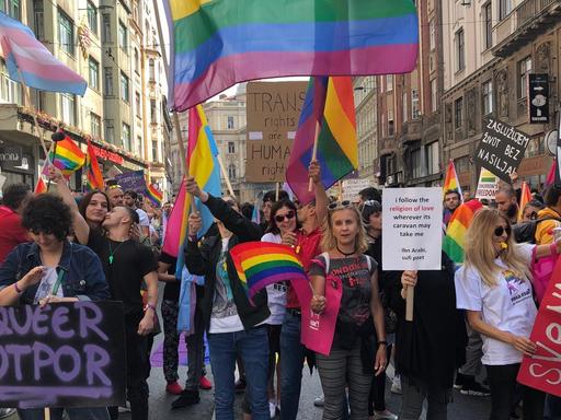 Die erste Pride Parade für die Rechte von LGBTQ-Menschen in den Straßen Sarajewos. Zu sehen sind Männer und Frauen, die Regenbogenfahnen schwenken und Transparente hochhalten.
