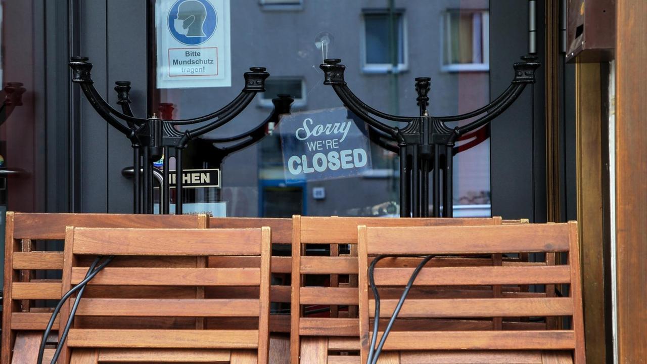 Zusammengeklappte Stühle und Tische vor einem Berliner Restaurant. Schild mit Schriftzug: Sorry, we are closed. Zusammengeklappte Stühle und Tische vor einem Berliner Restaurant. Schild mit Schriftzug: Sorry, we are closed.