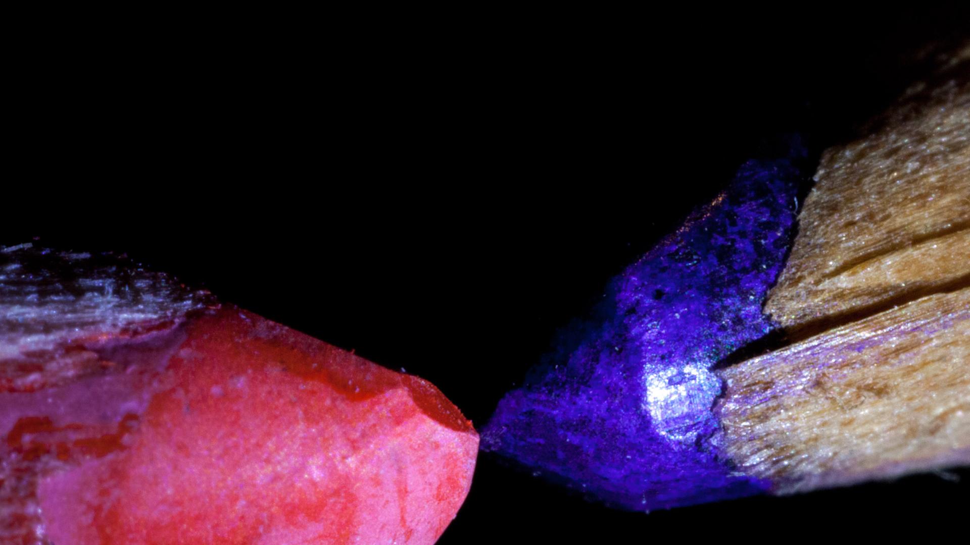 Ein roter und ein blauer Zeichenstift liegen sich gegenüber auf dem Tisch. Ein roter und ein blauer Zeichenstift liegen sich gegenüber auf dem Tisch.