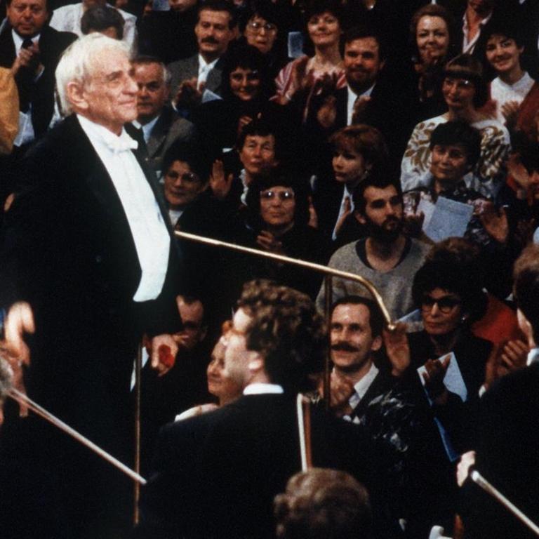 Ein weißhaariger Mann steht auf der Bühne und erhält Beifall vom Publikum, das dicht bei ihm steht - hin und wieder ist einer der roten Sessel des Konzerthauses zu sehen.