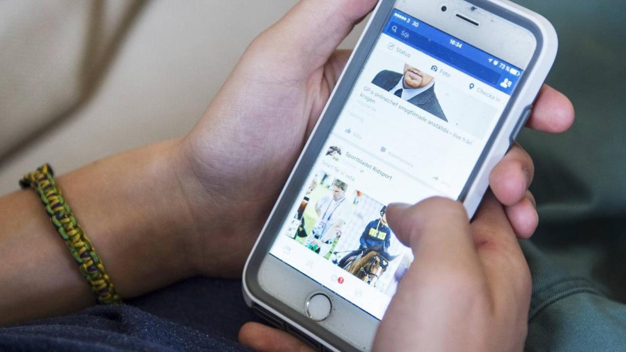 Ein Junge surft auf seinem Smartphone bei Facebook. Ein Junge surft auf seinem Smartphone bei Facebook.