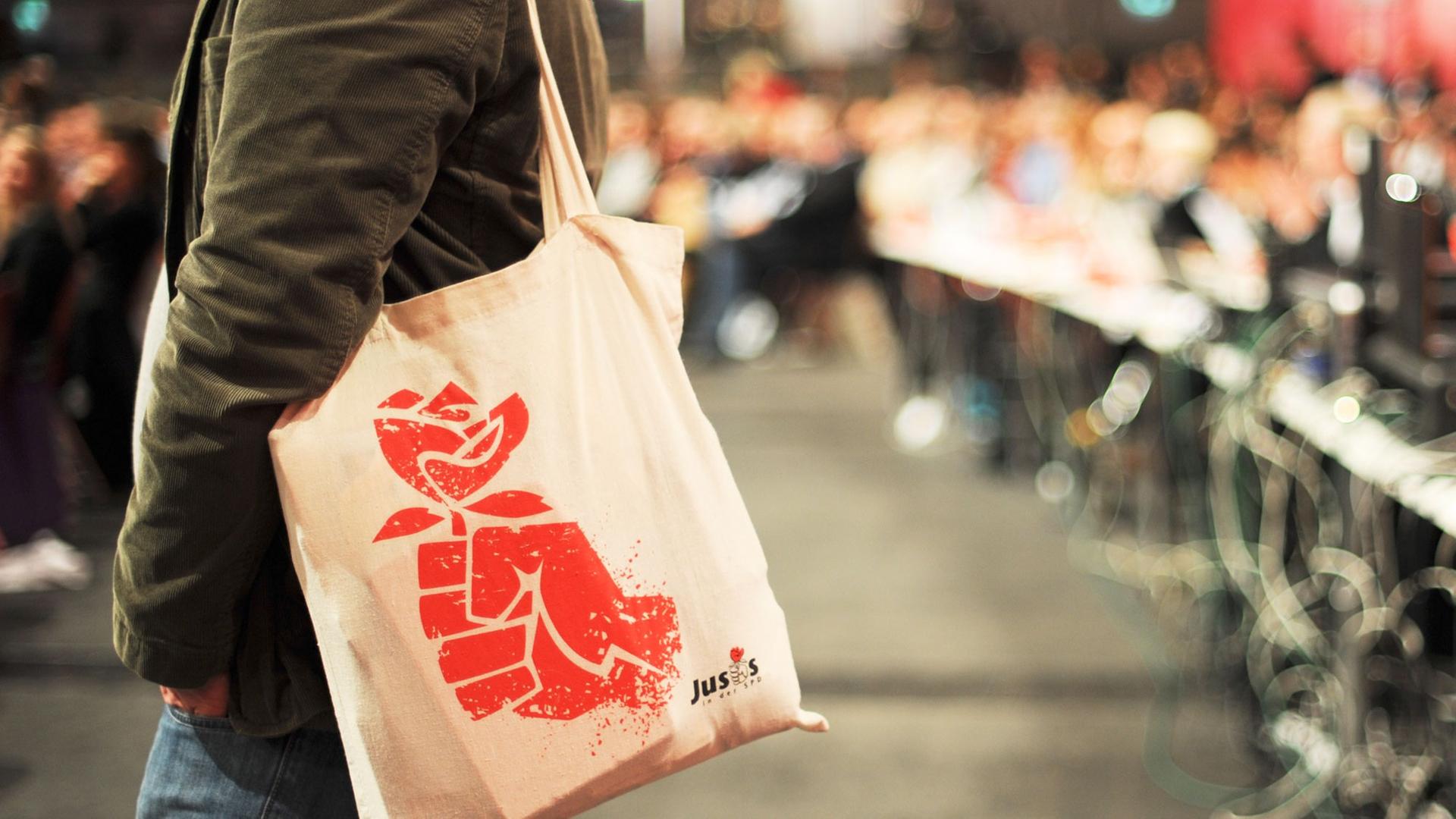 Ein Teilnehmer des SPD-Parteitages in Augsburg trägt einen Baumwoll-Beutel mit dem Logo der Jusos. Ein Teilnehmer des SPD-Parteitages in Augsburg trägt einen Baumwoll-Beutel mit dem Logo der Jusos.