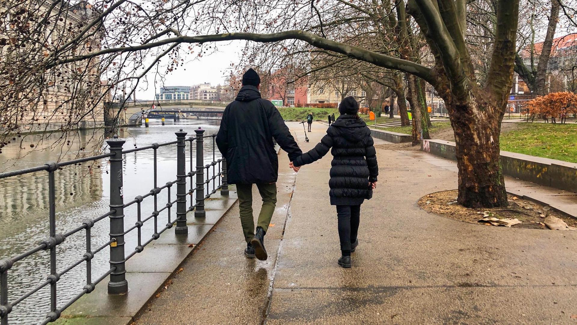 Ein Mann und deine Frau gehen Hand in Hand am Spree Ufer in Berlin spazieren. Ein Mann und deine Frau gehen Hand in Hand am Spree Ufer in Berlin spazieren.