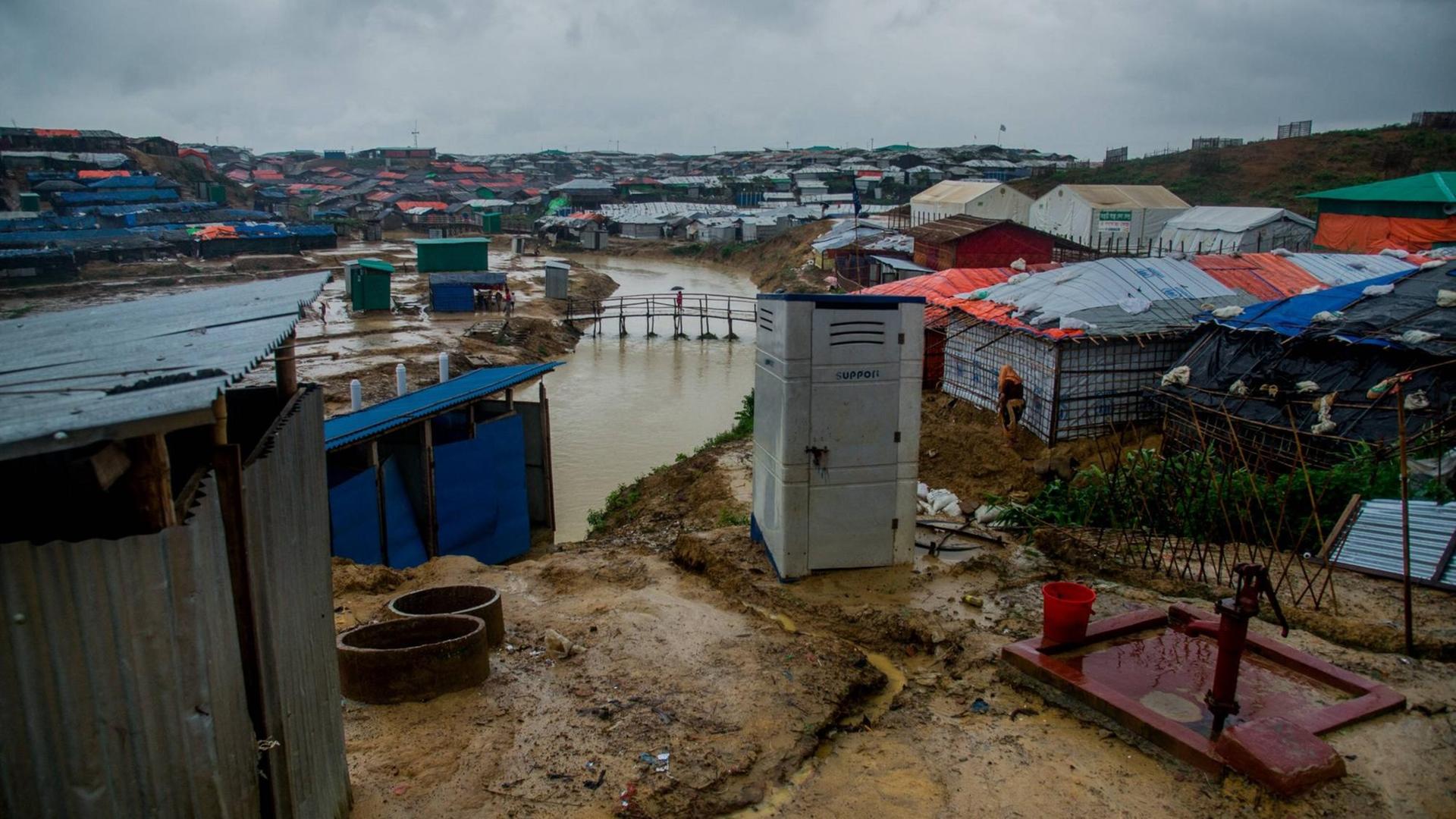 Blick über die aus Planen bestehenden Dächer der Hütten im Flüchtlingslager Kutupalong in Bangladesch im Juni 2018. Durch das Lager läuft ein Fluss, die Erde ist durchnässt und dreckig.