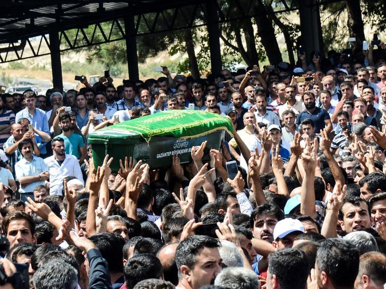Ein Sarg wird während der Beerdigungsprozession für ein Opfer des Anschlages auf eine Hochzeitsfeier im türkischen Gaziantep durch die Menge getragen.