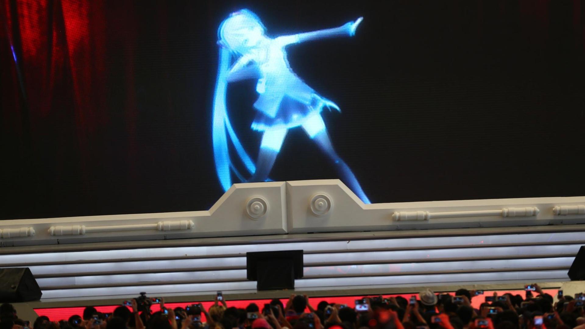 Eine Performance mit der digitalen Figur Hatsune Miku, vorne Zuschauer.