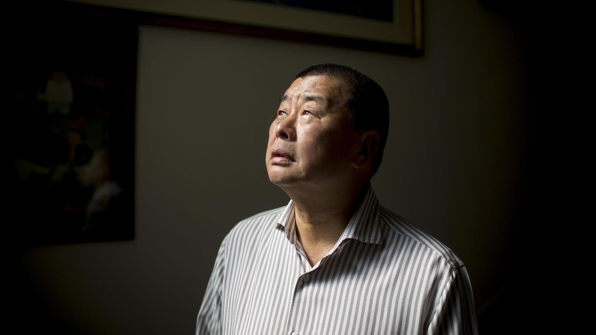 Jimmy Lai steht vor einer dunklen Wand und schaut ins Licht Jimmy Lai steht vor einer dunklen Wand und schaut ins Licht