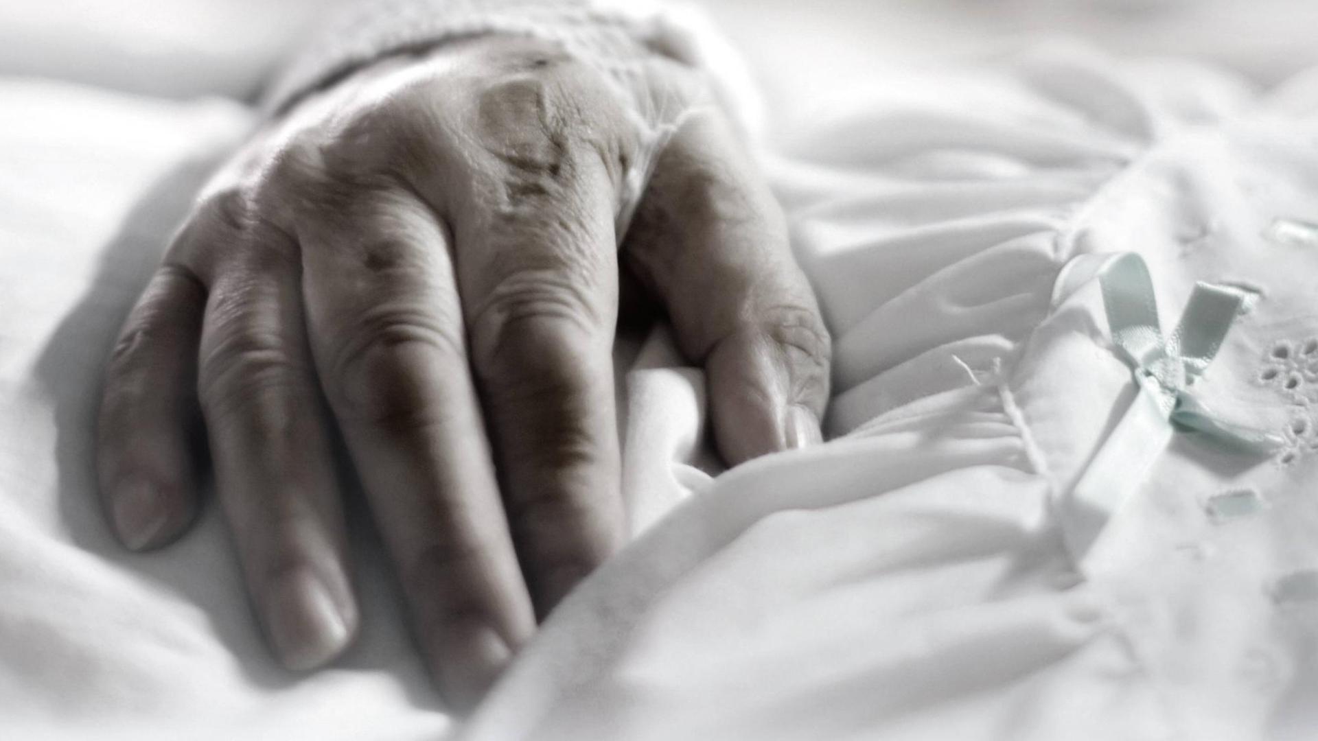 Hand einer alten Patientin auf weißem Bettzeug in einer Klinik Hand einer alten Patientin auf weißem Bettzeug in einer Klinik