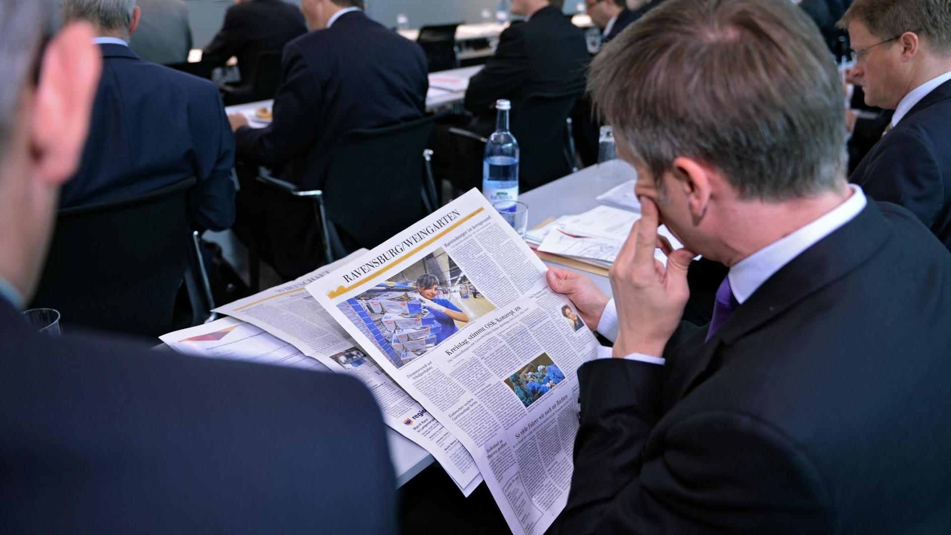 Die "Schwäbische Zeitung" wird bei einer Geschäftstagung von einem Mann im Anzug gelesen. Die "Schwäbische Zeitung" wird bei einer Geschäftstagung von einem Mann im Anzug gelesen.