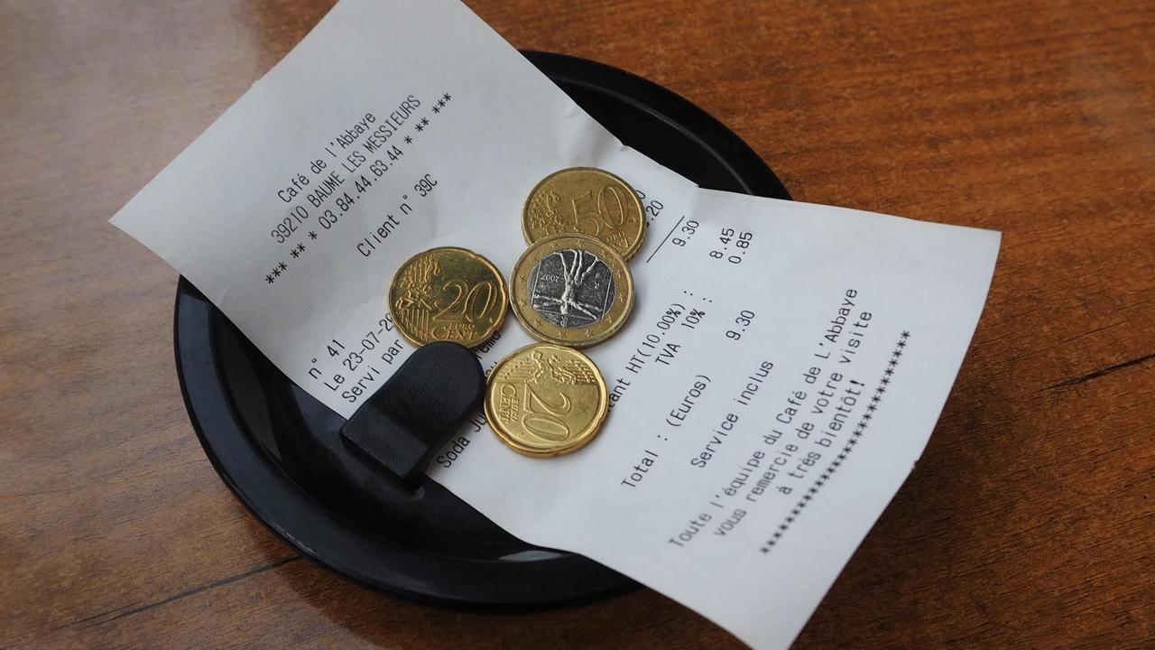 Eine Rechnung in einem französischen Kaffee auf einem Tellerchen - darauf liegt etwas Trinkgeld Eine Rechnung in einem französischen Kaffee auf einem Tellerchen - darauf liegt etwas Trinkgeld