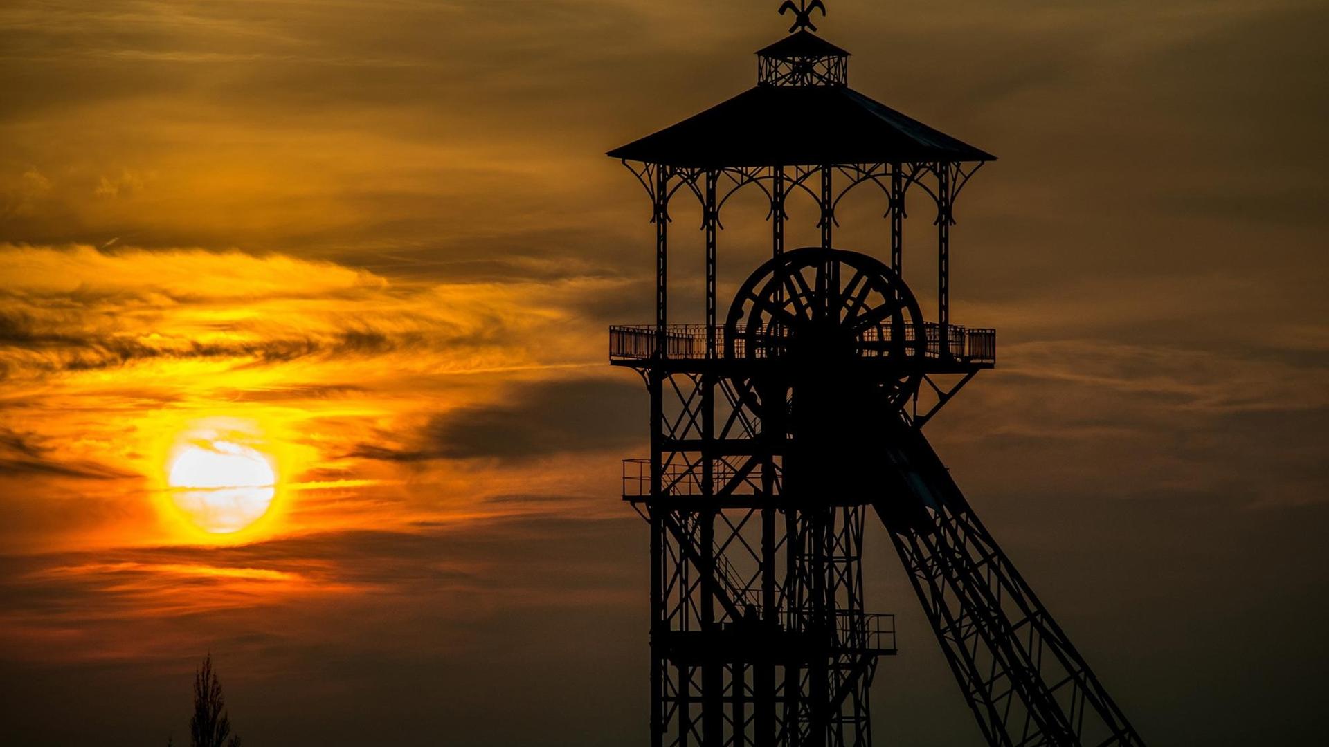 Sonnenaufgang über dem Nordfranzösischen Kohlerevier, im Vordergrund ein altes Fördergerüst Sonnenaufgang über dem Nordfranzösischen Kohlerevier, im Vordergrund ein altes Fördergerüst