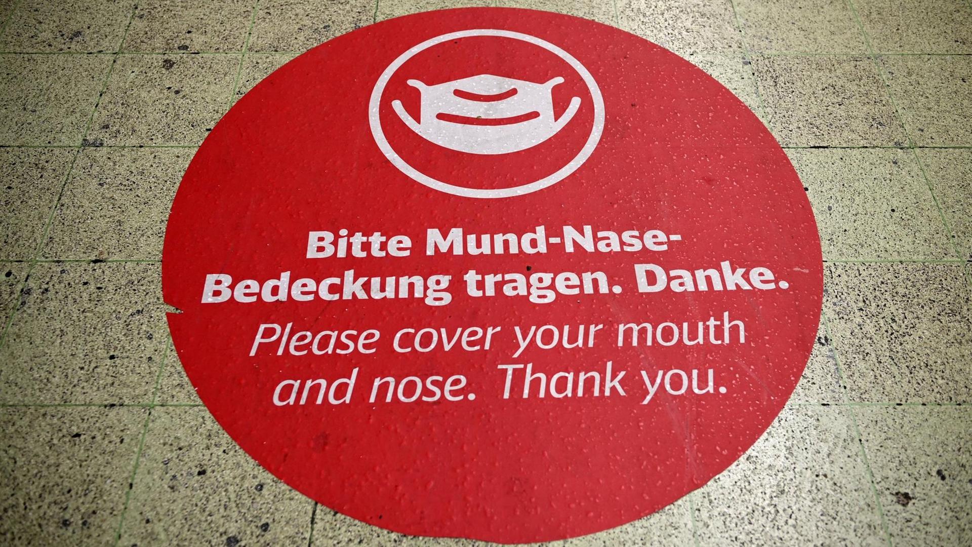 Am Boden ist das rote Bild einer Maske zu sehen und dazu der Hinweis: "Bitte Mund-Nase-Bedeckung tragen. Danke". Am Boden ist das rote Bild einer Maske zu sehen und dazu der Hinweis: "Bitte Mund-Nase-Bedeckung tragen. Danke".