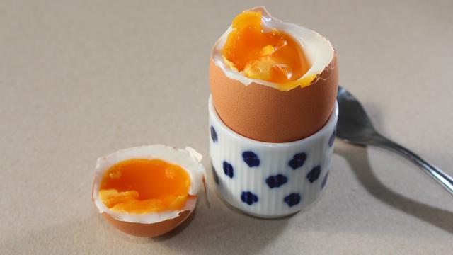 Ein wachsweich gekochtes Hühnerei mit brauner Schale in einem Eierbecher.