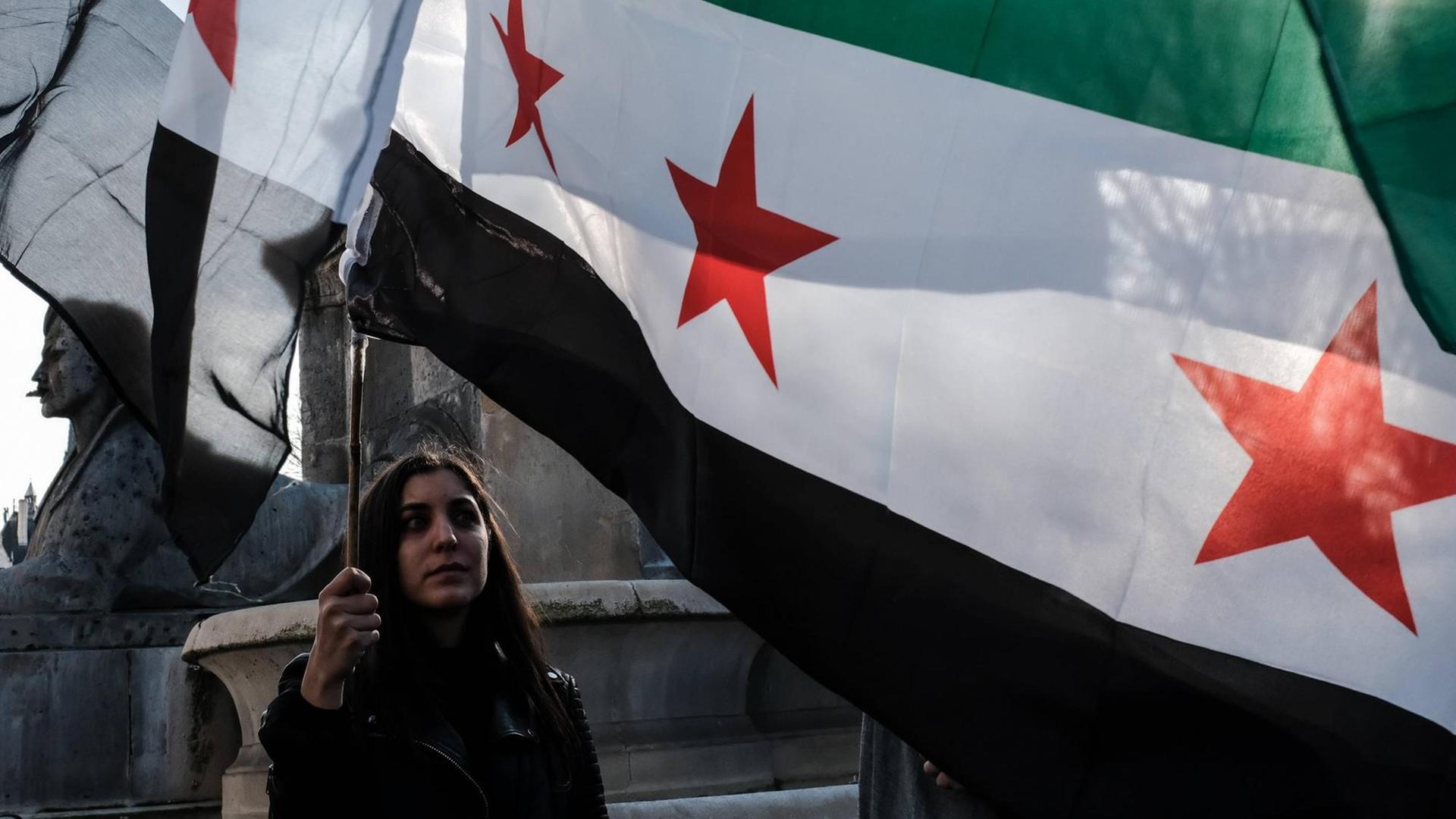 In Frankreich protestieren Aktivisten gegen die Bombardierungen in Syrien: Aufnahme vom 11. April 2018. Eine junge Frau hält eine syrische Flagge hoch. In Frankreich protestieren Aktivisten gegen die Bombardierungen in Syrien: Aufnahme vom 11. April 2018. Eine junge Frau hält eine syrische Flagge hoch.