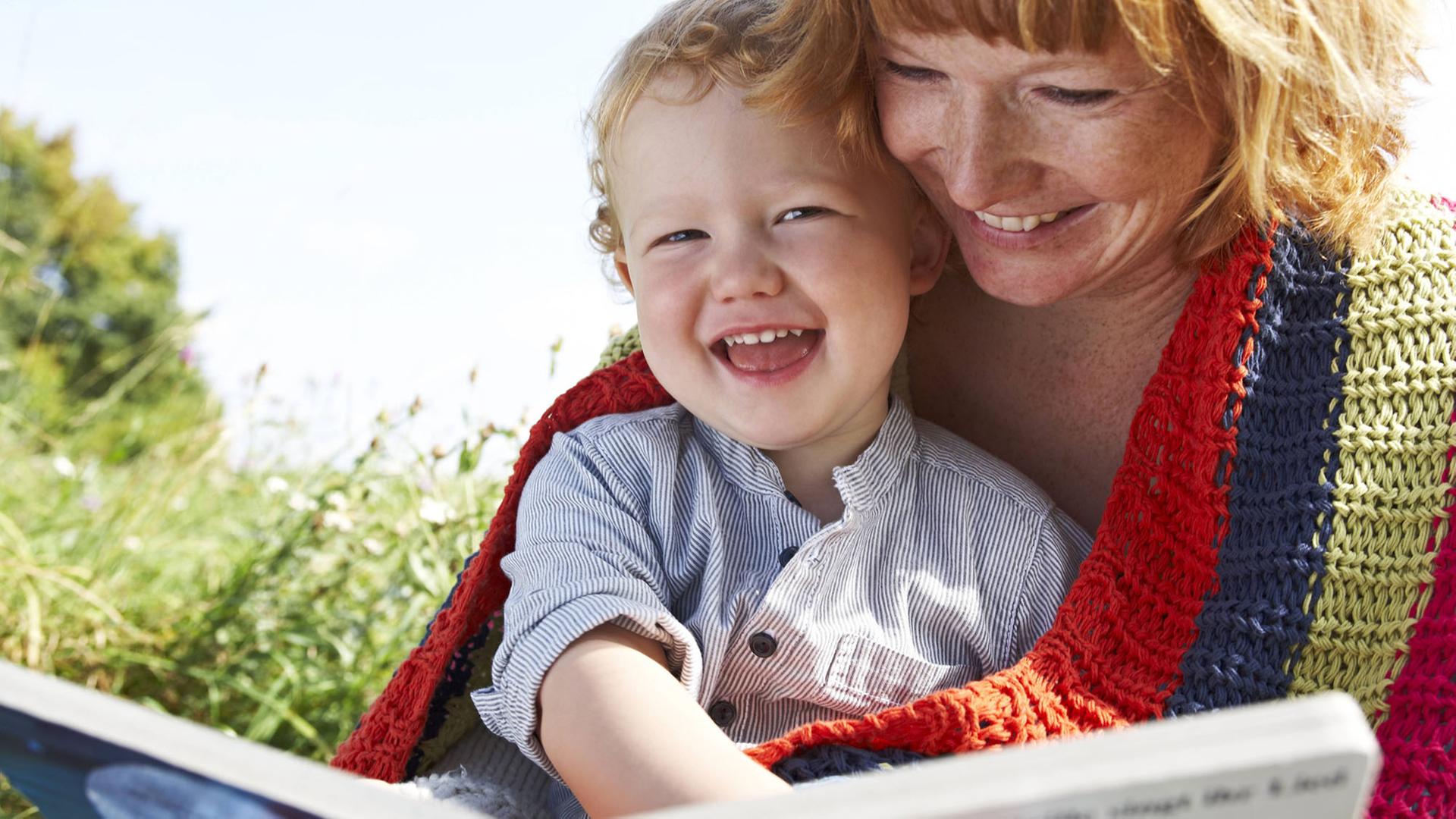 Eine Mutter und ihr Sohn lesen glücklich lachend gemeinsam ein Kinderbuch. Eine Mutter und ihr Sohn lesen glücklich lachend gemeinsam ein Kinderbuch.