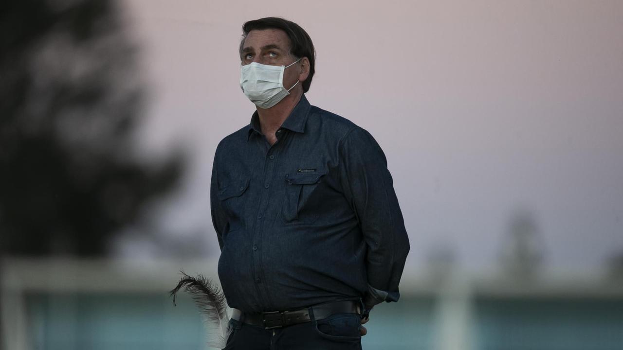 Der brasilianische Präsident trägt eine Atemschutzmaske und schaut in den Himmel. Der brasilianische Präsident trägt eine Atemschutzmaske und schaut in den Himmel.