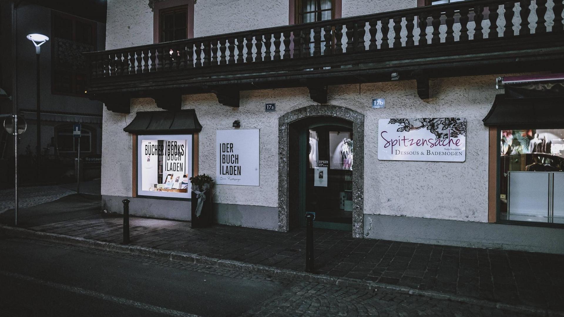 In der Dämmerung ist bei leerer Starße das beleuchtete Schaufenster eines Buchladens zu erkennen. In der Dämmerung ist bei leerer Starße das beleuchtete Schaufenster eines Buchladens zu erkennen.