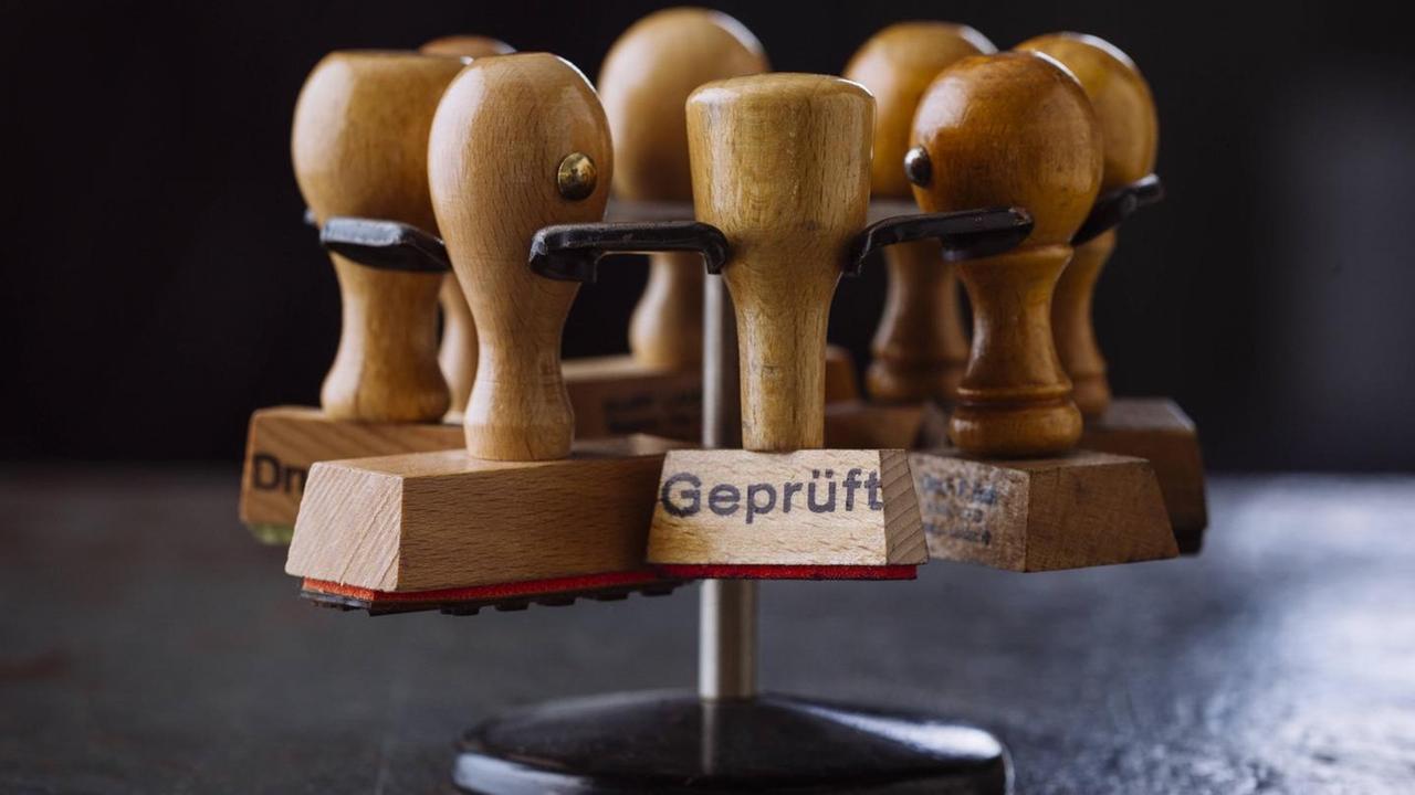 Ein Halter mit ihreren Stempeln. Auf dem vordersten Stempel steht "Geprüft". Ein Halter mit ihreren Stempeln. Auf dem vordersten Stempel steht "Geprüft".