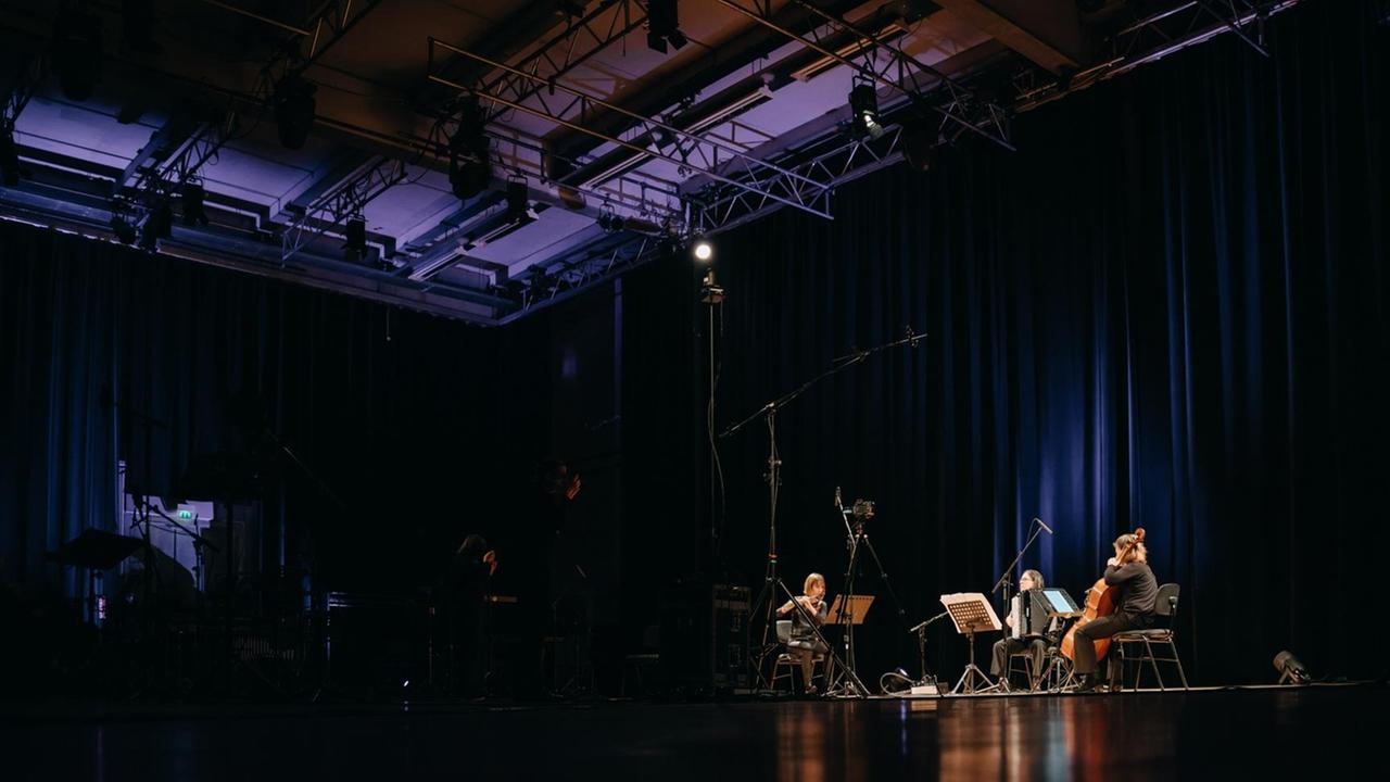 Drei Musiker spielen in einer großen, leeren Halle konzentriert Musik. Drei Musiker spielen in einer großen, leeren Halle konzentriert Musik.