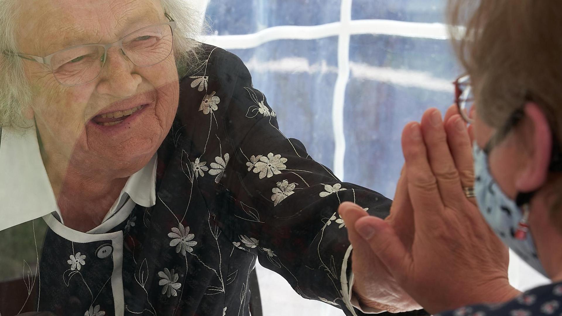 Mutter und Tochter in einem Zelt vor dem Seniorenheim Maria Königin, geschützt durch eine Trennscheibe (aufgenommen am 10.05.2020 in Mainz). Mutter und Tochter in einem Zelt vor dem Seniorenheim Maria Königin, geschützt durch eine Trennscheibe (aufgenommen am 10.05.2020 in Mainz).