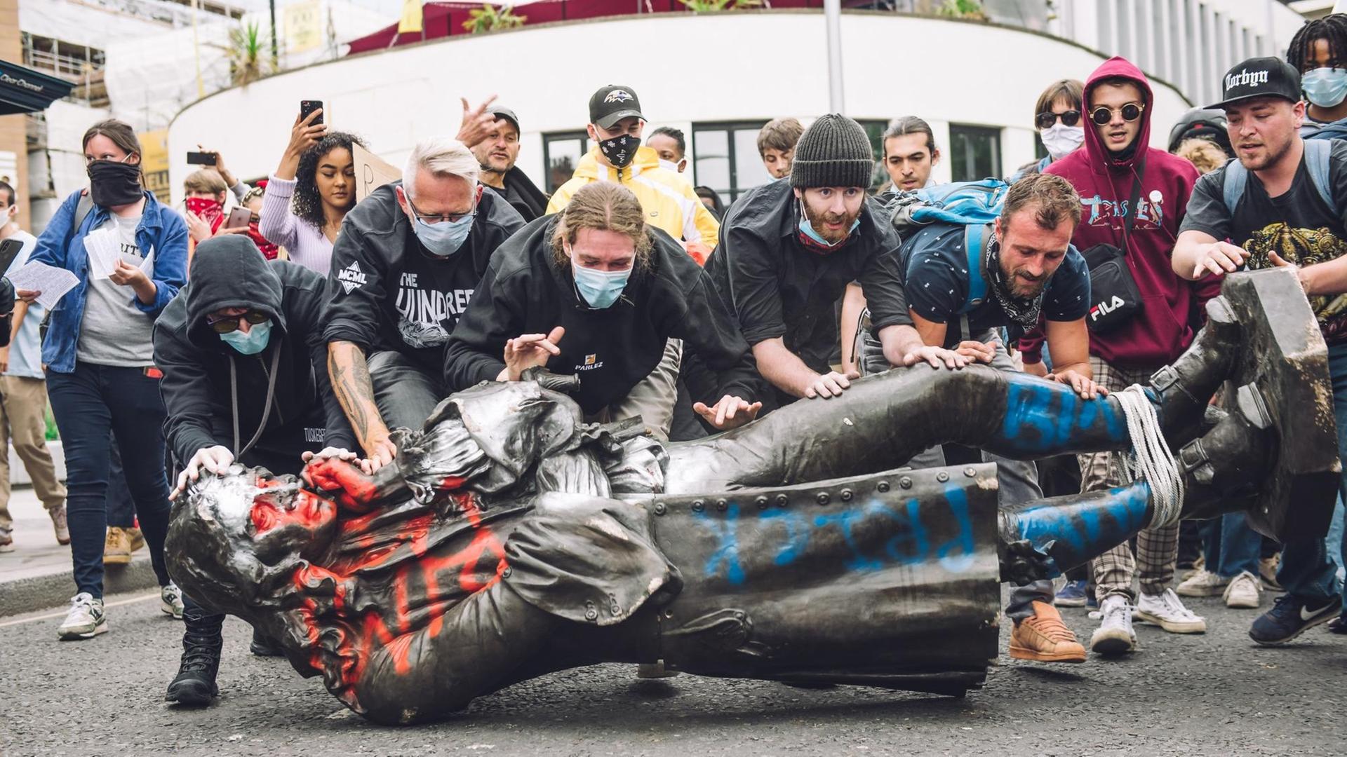 Demonstranten schieben die Statur von Edward Colston richtung Wasser. Demonstranten schieben die Statur von Edward Colston richtung Wasser.