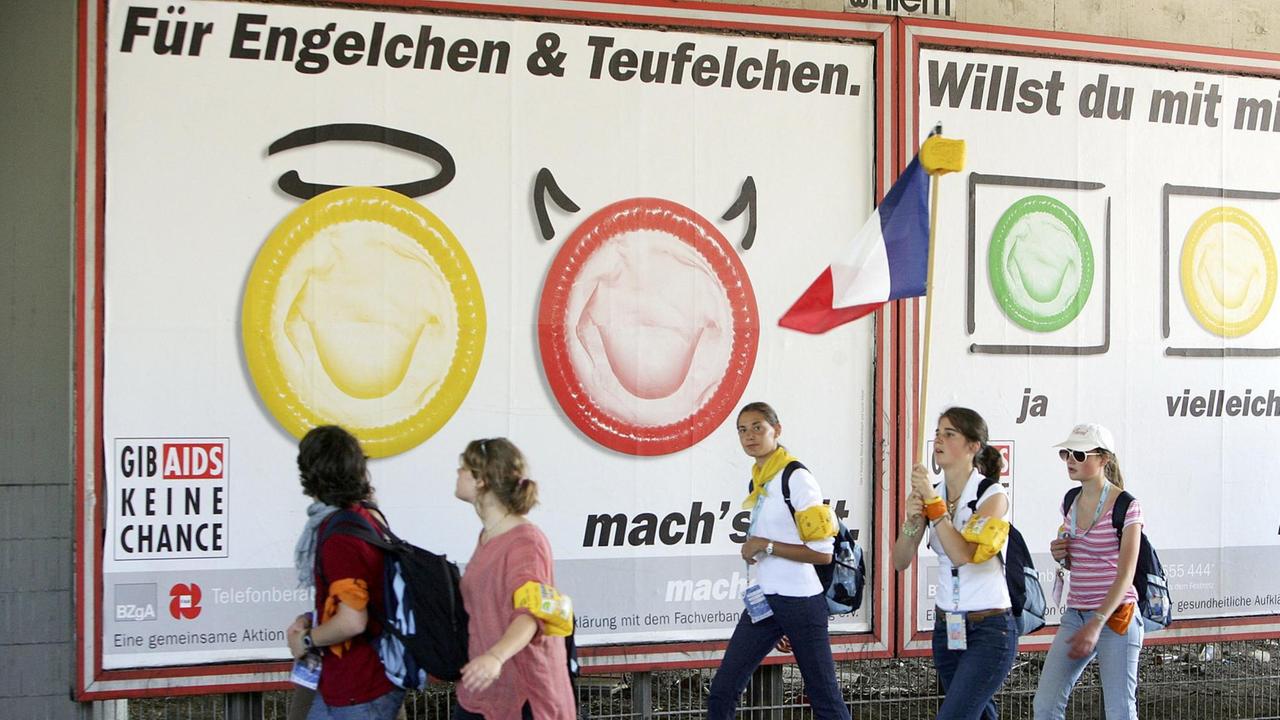 Teilnehmer des 20. katholischen Weltjugendtages spazieren am Mittwoch, 17.08.05, in der Kölner Innenstadt an einer Kondomwerbung vorbei. | Verwendung weltweit Teilnehmer des 20. katholischen Weltjugendtages spazieren am Mittwoch, 17.08.05, in der Kölner Innenstadt an einer Kondomwerbung vorbei. | Verwendung weltweit