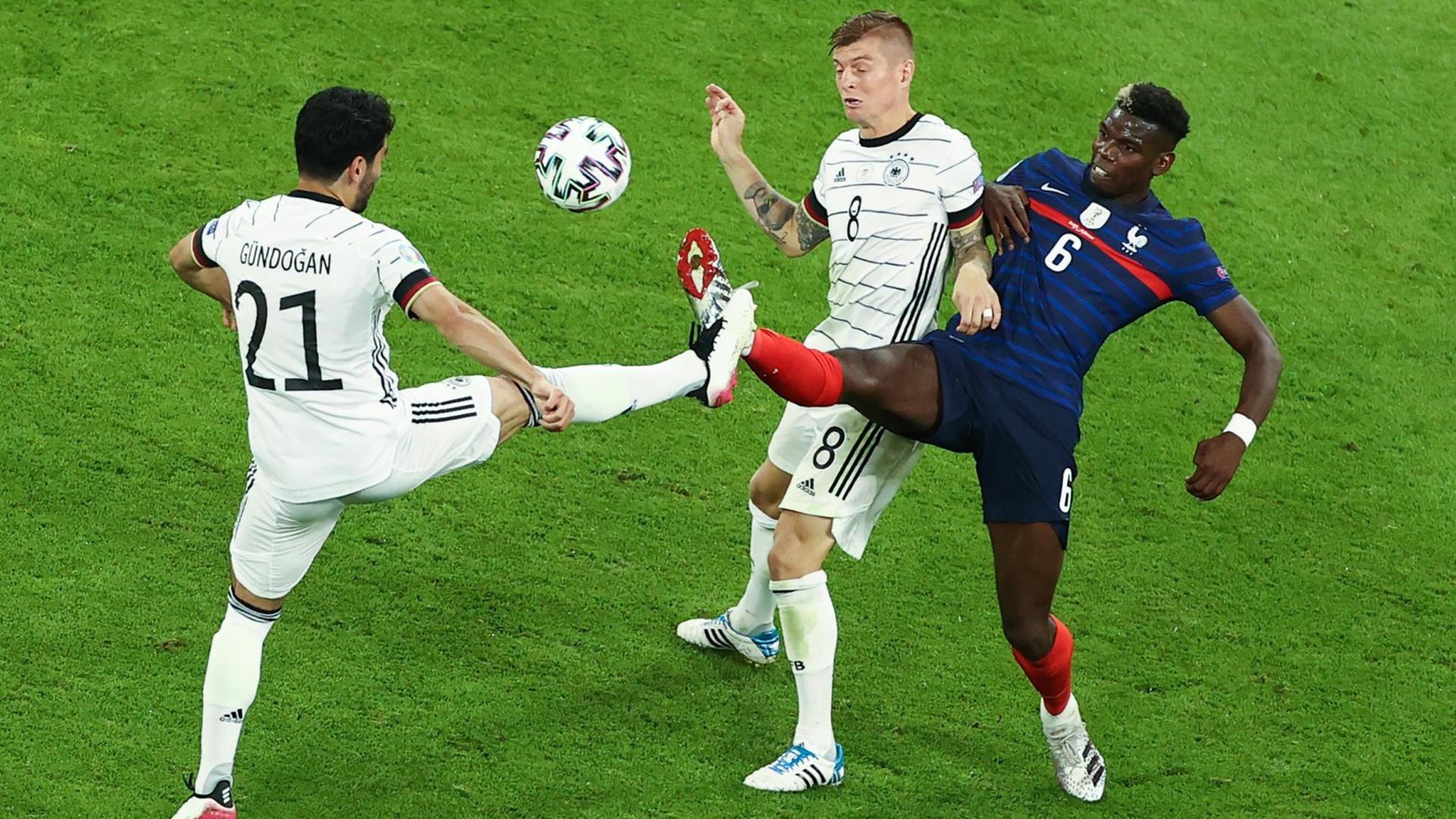 Fußball: EM, Frankreich - Deutschland, Vorrunde, Gruppe F, 1. Spieltag in der EM-Arena München. Ilkay Gündogan (Deutschland) und Toni Kroos (Deutschland, M) in Aktion mit Paul Pogba (Frankreich). I Fußball: EM, Frankreich - Deutschland, Vorrunde, Gruppe F, 1. Spieltag in der EM-Arena München. Ilkay Gündogan (Deutschland) und Toni Kroos (Deutschland, M) in Aktion mit Paul Pogba (Frankreich). I