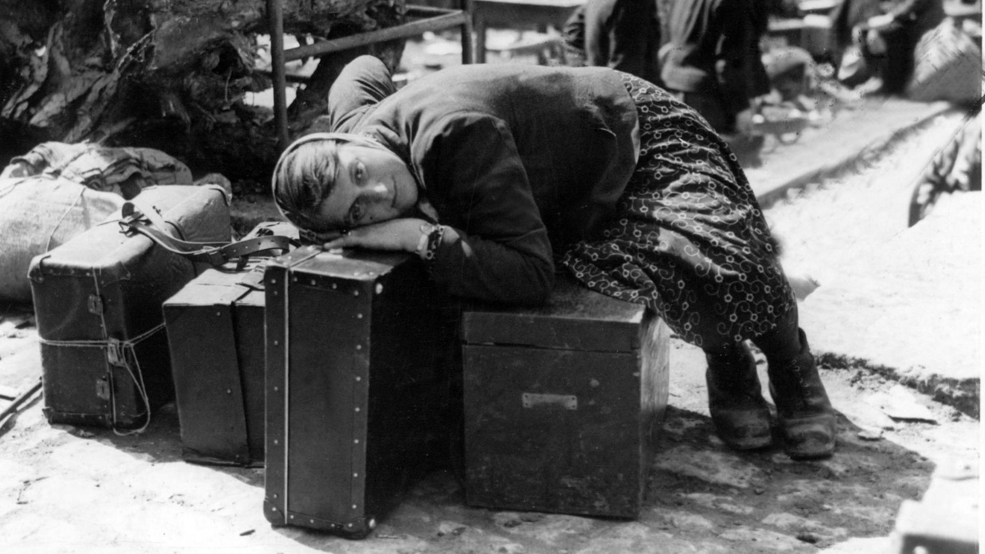 Eine erschöpfte russische Zwangsarbeiterin ruht sich im April 1945 in der Sammelstelle für Zwangsverschleppte in Würzburg auf Gepäckstücken aus. Sie war von Einheiten der 7. amerikanischen Armee befreit worden und wartet nun auf ihre Repatriierung