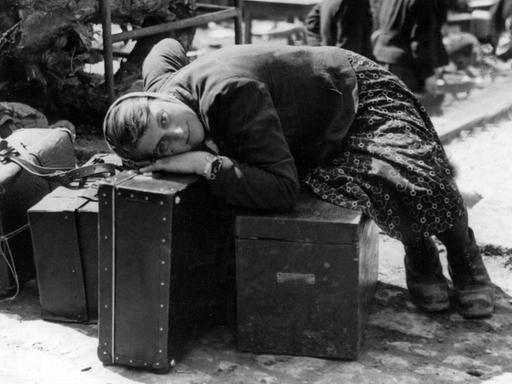 Eine erschöpfte russische Zwangsarbeiterin ruht sich im April 1945 in der Sammelstelle für Zwangsverschleppte in Würzburg auf Gepäckstücken aus. Sie war von Einheiten der 7. amerikanischen Armee befreit worden und wartet nun auf ihre Repatriierung