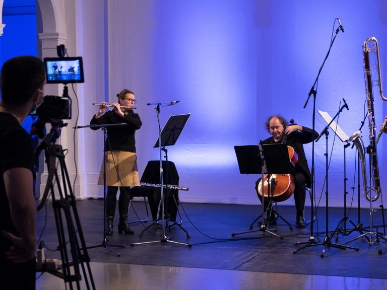 Ein Trio des Ensembles wird von einem Kameramann mit Stativ auf der Bühne gefilmt