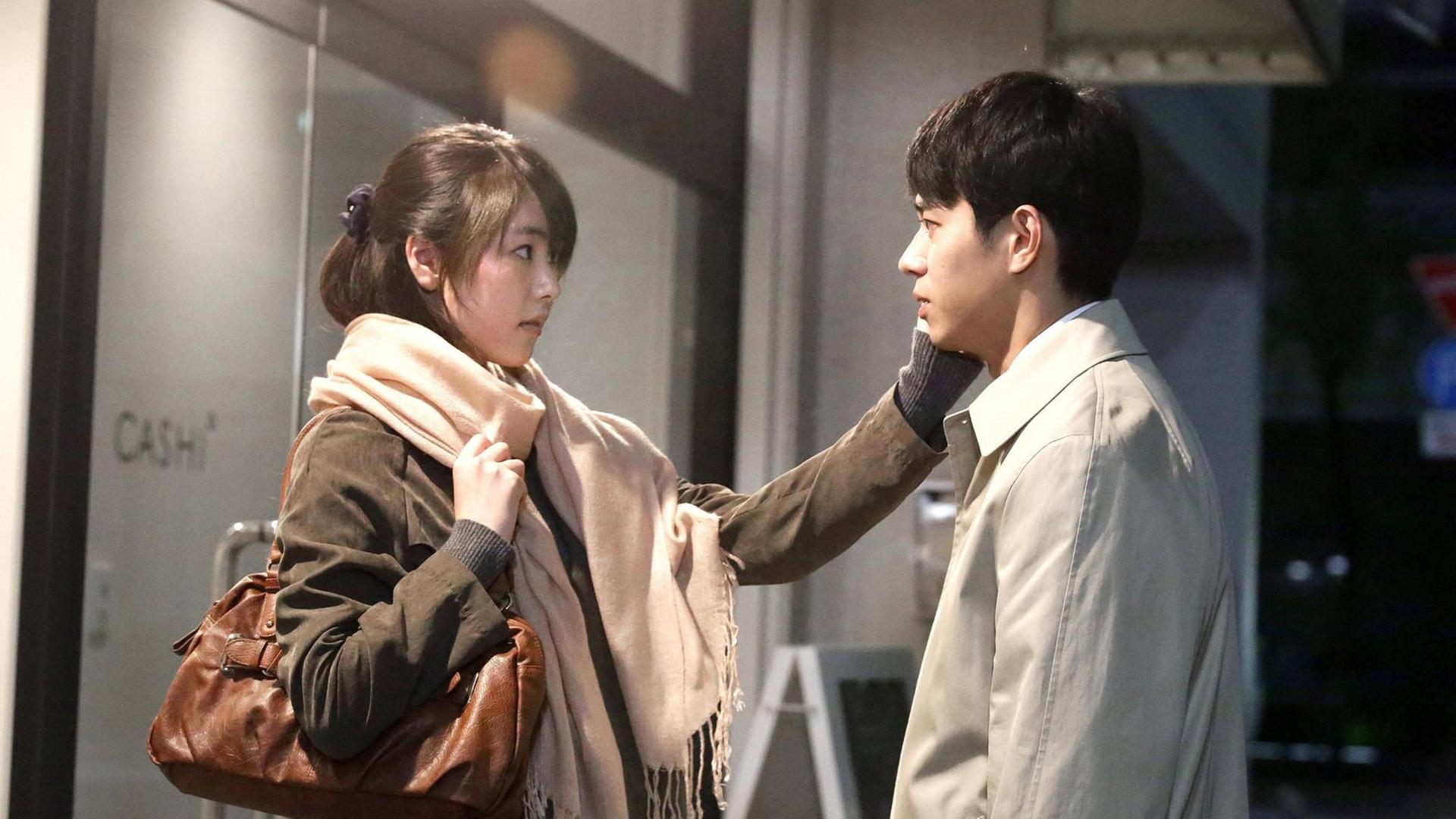 Szenenbild aus dem Film "ASAKO I & II" des japanischen Regisseurs Ryusuke Hamaguchi, in der die japanische Schauspierin Erika Karata dem japanischen Schauspieler Masahiro Higashide von der Seite gesehen mit Abstand gegenübersteht und ihm die linke Hand an seine rechte Wange legt. Szenenbild aus dem Film "ASAKO I & II" des japanischen Regisseurs Ryusuke Hamaguchi, in der die japanische Schauspierin Erika Karata dem japanischen Schauspieler Masahiro Higashide von der Seite gesehen mit Abstand gegenübersteht und ihm die linke Hand an seine rechte Wange legt.