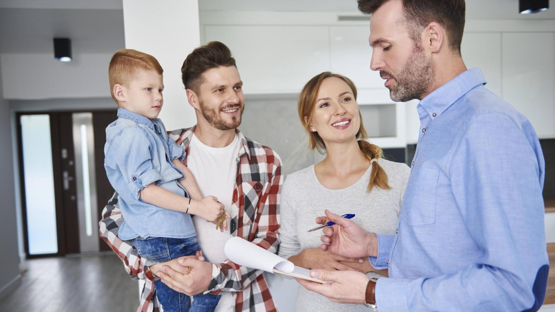 Familie steht in Neubauhaus und spricht mit einem Makler. Familie steht in Neubauhaus und spricht mit einem Makler.