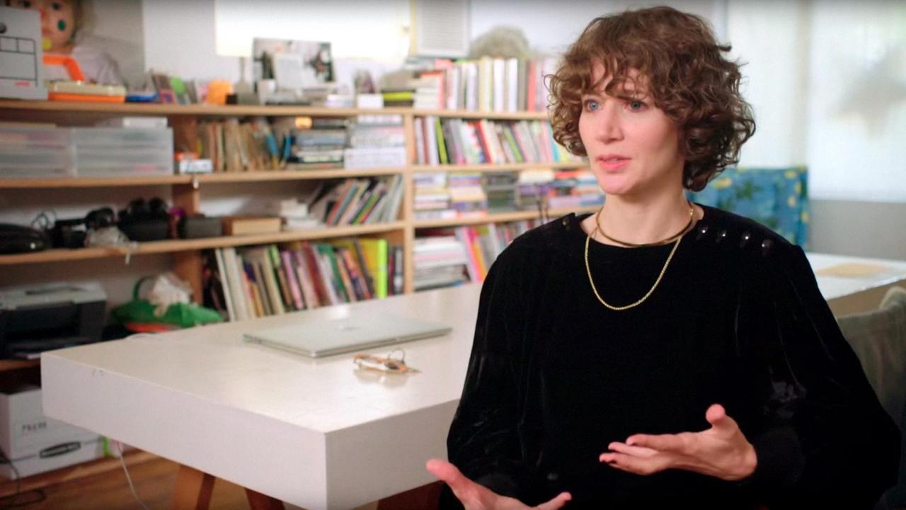 Die Regisseurin Miranda July sitzt in einem Büro. Im Hintergrund sind ein Tisch und ein Bücherregal zu sehen. Die Regisseurin Miranda July sitzt in einem Büro. Im Hintergrund sind ein Tisch und ein Bücherregal zu sehen.