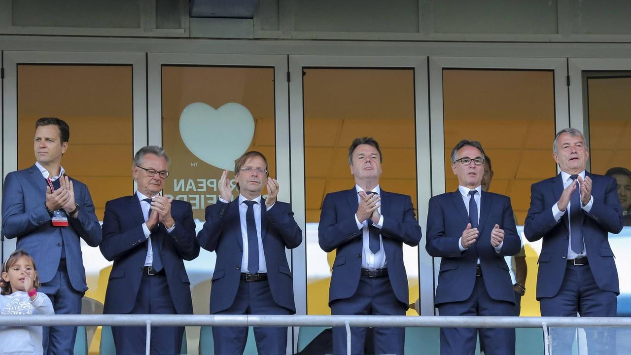 Oliver Bierhoff, Heribert Bruchhagen, Helmut Sandrock und Wolfgang Niersbach stehen auf einer Tribüne und applaudieren. Oliver Bierhoff, Heribert Bruchhagen, Helmut Sandrock und Wolfgang Niersbach stehen auf einer Tribüne und applaudieren.