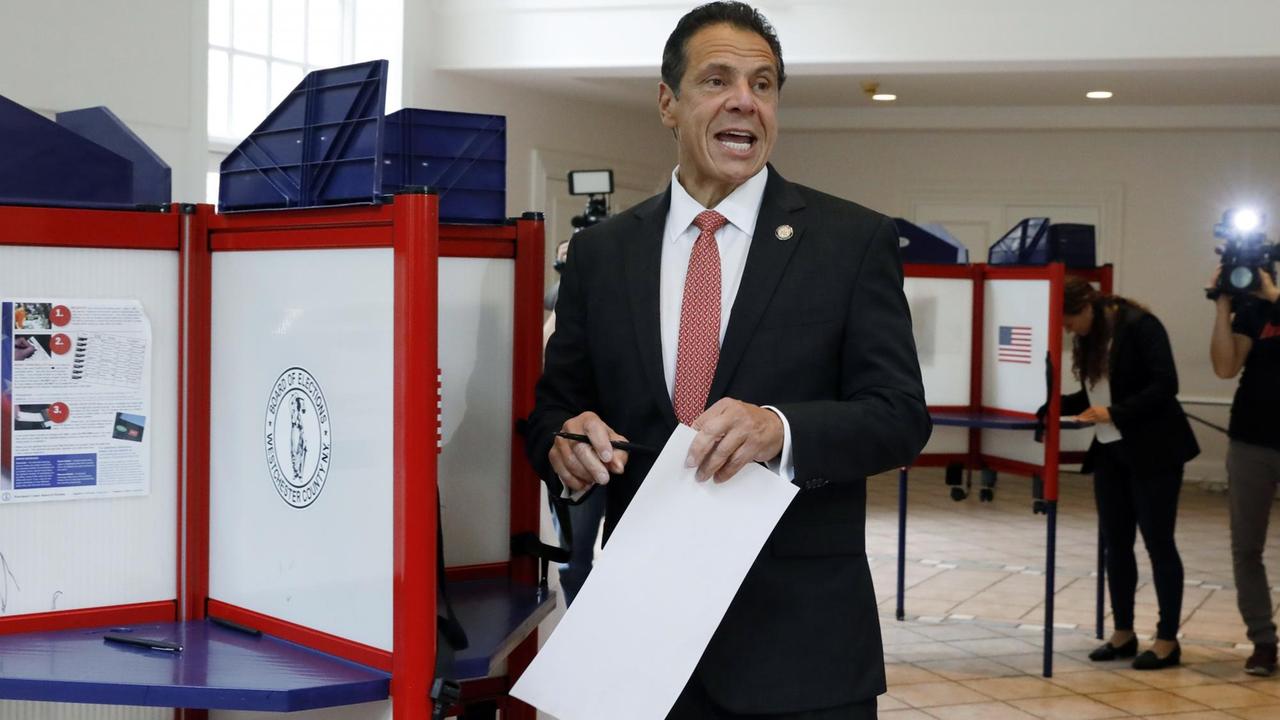Das Bild zeigt Andrew Cuomo, der sich bei der Vorwahl in New York gegen die Schauspielerin Nixon durchgesetzt hat, in einem Wahlraum. Er trägt einen schwarzen Anzug, ein weißes Hemd mit rotem Schlips und hält den Wahlzettel in der linken Hand. Das Bild zeigt Andrew Cuomo, der sich bei der Vorwahl in New York gegen die Schauspielerin Nixon durchgesetzt hat, in einem Wahlraum. Er trägt einen schwarzen Anzug, ein weißes Hemd mit rotem Schlips und hält den Wahlzettel in der linken Hand.
