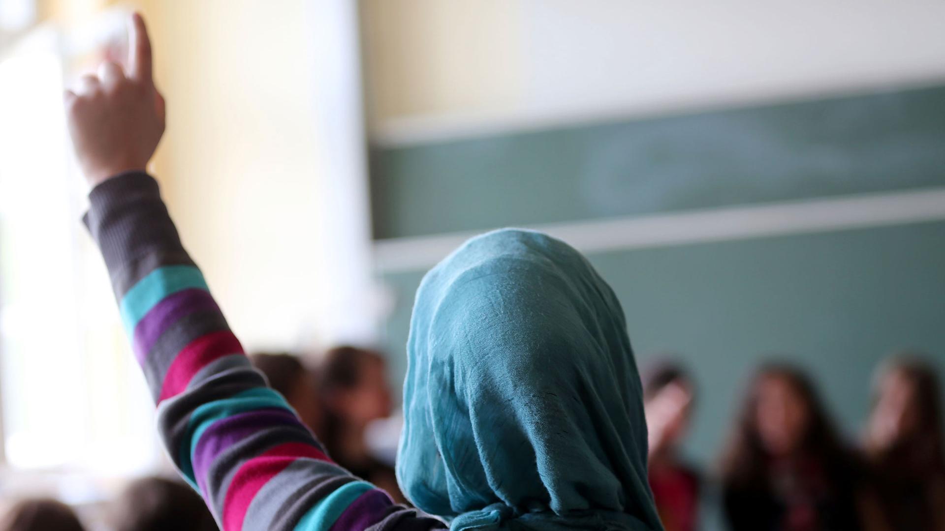 Eine Schülerin mit Kopftuch meldet sich im Unterricht Eine Schülerin mit Kopftuch meldet sich im Unterricht
