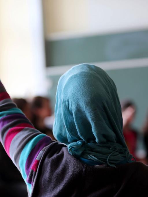 Eine Schülerin mit Kopftuch meldet sich im Unterricht