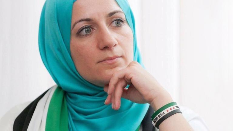 Nahla Osman mit Kopftuch, vor einem Fenster sitzend. Nahla Osman mit Kopftuch, vor einem Fenster sitzend.