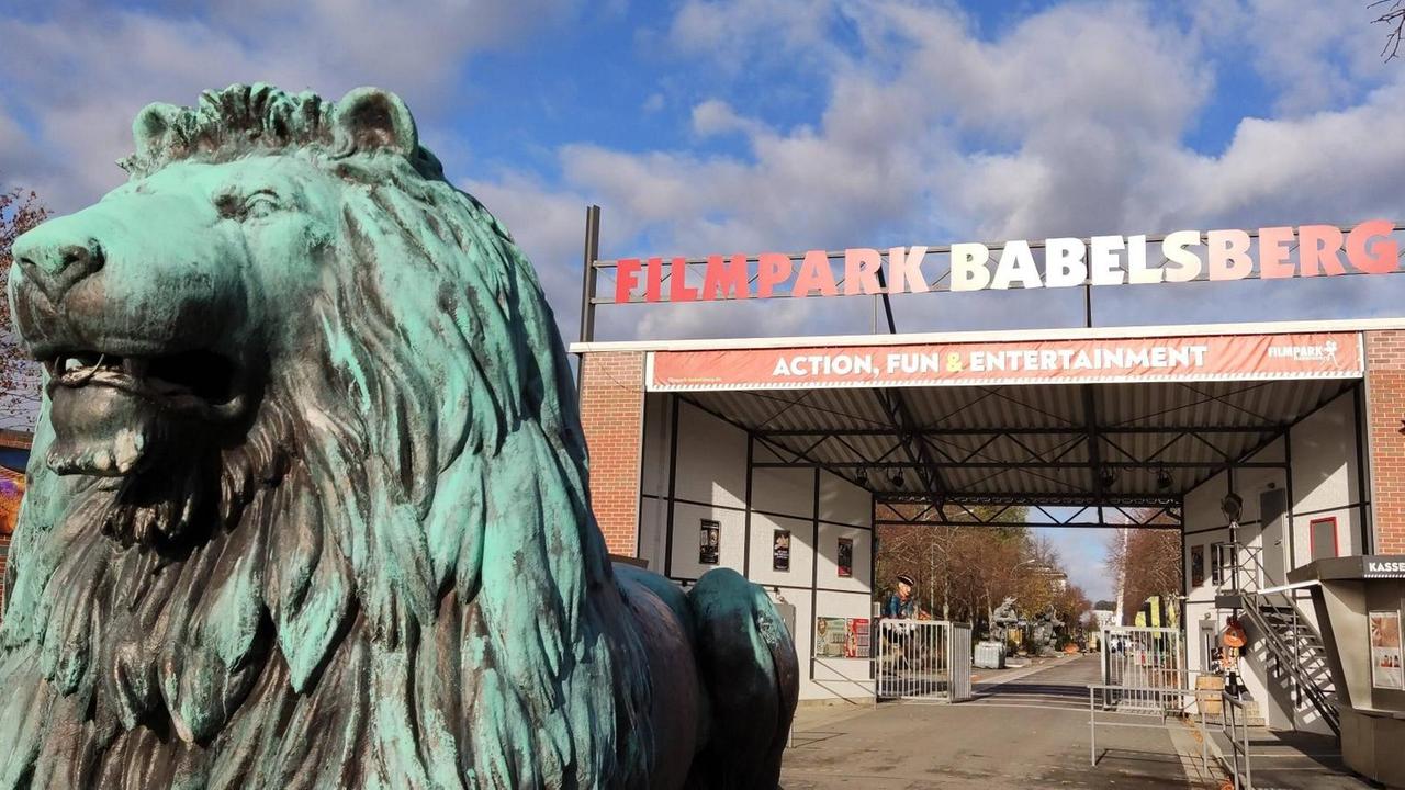 Das Eingangstor des Filmparks Babelsberg. Links im Bildvordergrund eine Löwenskulptur. Das Eingangstor des Filmparks Babelsberg. Links im Bildvordergrund eine Löwenskulptur.